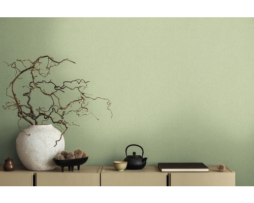 Dekorativní scéna s vázou, větvemi, čajovou konvicí a dalšími dekorativními prvky na komodě před stěnou