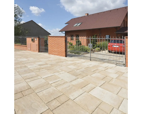 Příjezdová cesta s dlažebními kostkami, plotem a obytným domem v pozadí