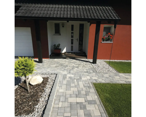 Dlážděná cesta k domu s dlažebními kostkami a trávníky.