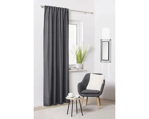 Šedý závěs se stahovací páskou před oknem ve světlé místnosti.