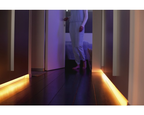 Chodba s LED osvětlením pod skříněmi a osobou v pozadí