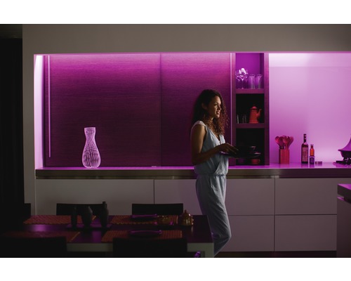 Žena s talíři v moderní kuchyni s dekorativním osvětlením