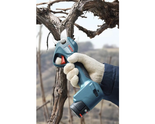 Ruka v rukavici stříhá větev elektronickými nůžkami