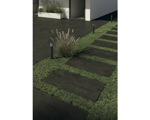 Kamenné terasové desky tvoří cestu zahradou, osvětlenou zahradními lampami.