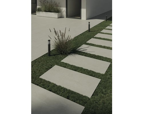 Kamenné chodníkové desky v zahradě s trávníkem a dekorativními lampami