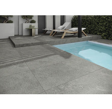 Exteriér se šedými dlaždicemi, bazénem a lehátky