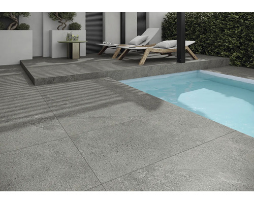 Šedé terasové dlaždice vedle bazénu s lehátky