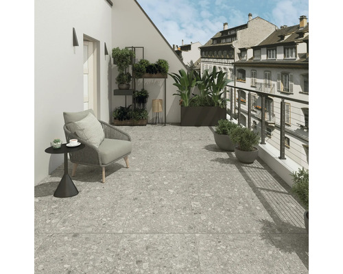Balkon s šedou dlažbou, židlí a rostlinami