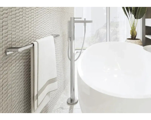 Světlá koupelna s vanou, držákem na ručníky a strukturovanými obkladačkami