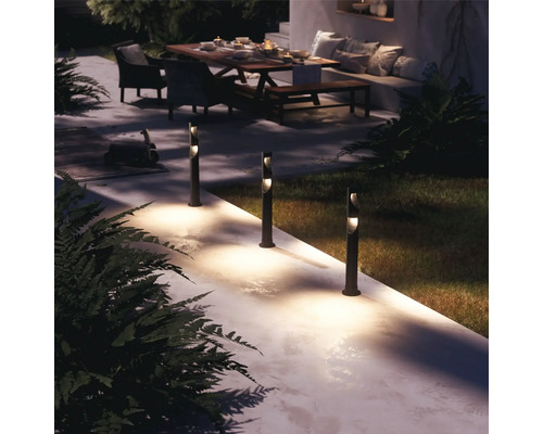 Osvětlená zahradní cesta s patníkovými svítidly, posezení v pozadí.