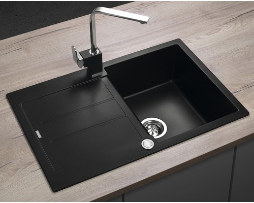 Černý kuchyňský dřez s odkapávací plochou a baterií na pracovní desce.
