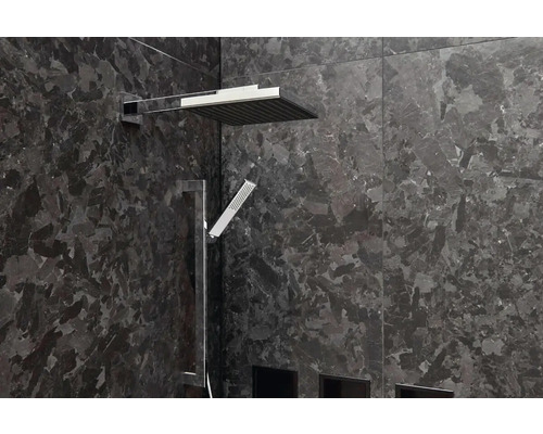 Moderní sprcha s horní a ruční sprchou před tmavou kamennou stěnou.