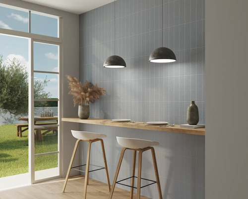 Světlá kuchyně s modrými obkládačkami, barovými stoličkami a výhledem ven