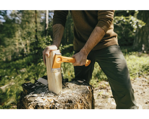 Muž štípe dřevo sekerou Fiskars na pařezu