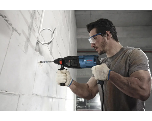 Muž vrtá díru do zdi s příklepovou vrtačkou Bosch