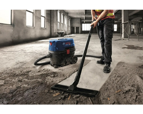 Řemeslník čistí staveniště průmyslovým vysavačem Bosch.
