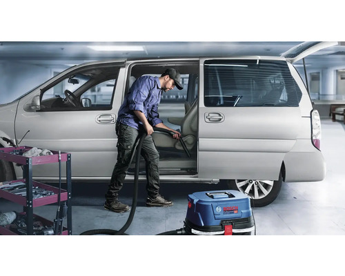 Muž čistí interiér auta vysavačem Bosch Professional.