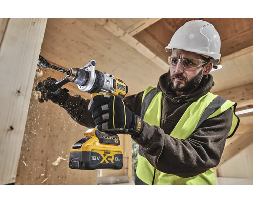 Řemeslník vrtá otvor do dřevěné desky pomocí akumulátorové vrtačky DeWalt