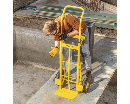 Osoba používá žlutý rudl Stanley k přesunu těžkého předmětu.