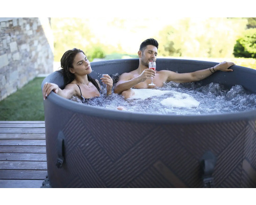 Pár relaxuje ve venkovní nafukovací vířivce s nápoji.