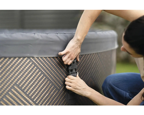 Osoba upevňuje kryt vířivky pomocí přezek