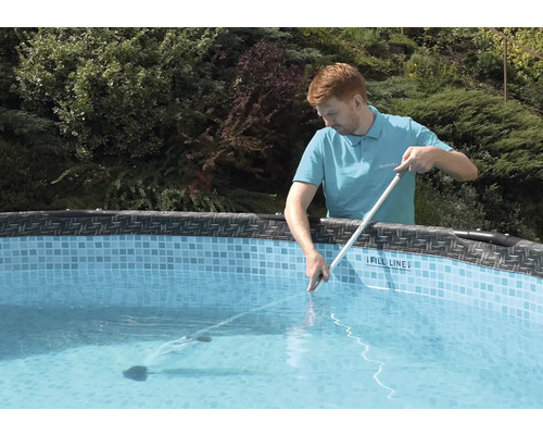 Muž čistí bazén pomocí čističe bazénu a tyče