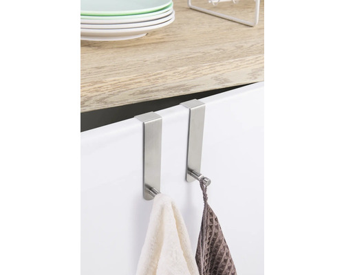 Dva kovové dveřní háčky s ručníky visí na dveřích skříně