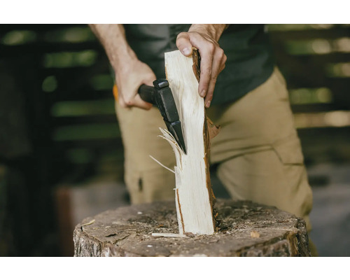 Osoba štípe sekerou kus dřeva na špalku.