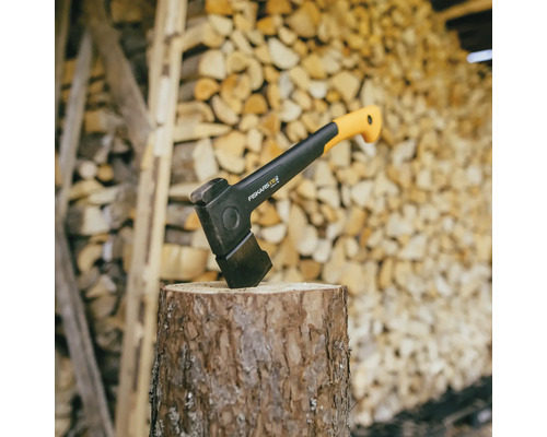 Štípací kladivo na pařezu před hromadou dřeva