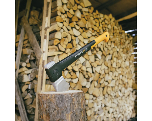 Sekera na pařezu před hromadou dřeva