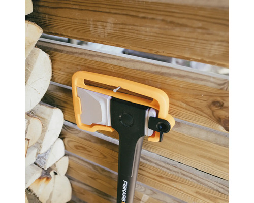 Sekera Fiskars s chráničem čepele před dřevěnou stěnou