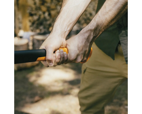 Detailní záběr osoby držící sekeru s černou hlavou a oranžovou rukojetí