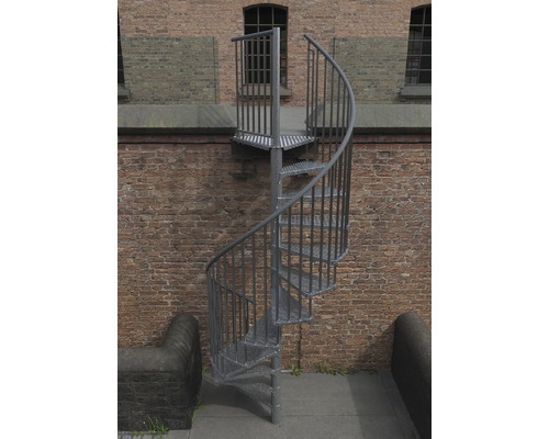 Kovové venkovní schodiště se spirálovým schodištěm před cihlovou zdí