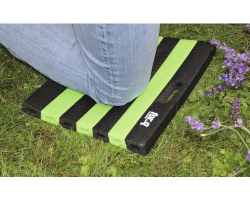 Osoba klečí na zahradní podložce se vzorem pruhů na trávníku