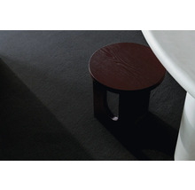 Detailní pohled na černý koberec s dřevěným odkládacím stolkem