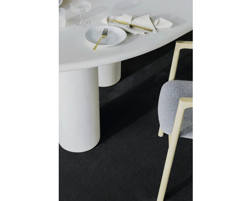 Detailní záběr místnosti s bílým stolem, židlí a tmavým kobercem