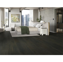 Ložnice s tmavou dřevěnou podlahou, postelí a bílým křeslem