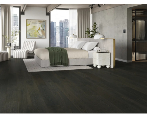 Ložnice s tmavou dřevěnou podlahou, postelí a bílým křeslem