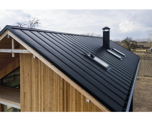 Pohled na dům s plechovou střechou, střešními okny a komínem