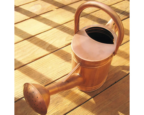 Kovová konev na dřevěném povrchu