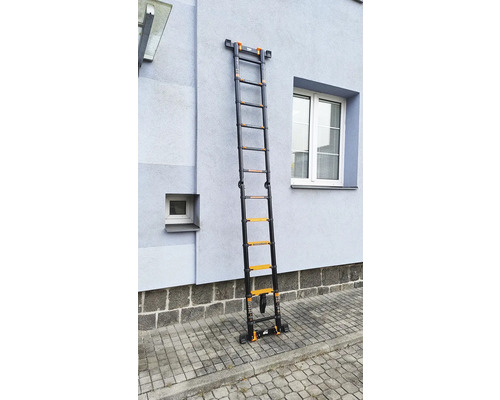 Rozložený teleskopický žebřík z kovu u stěny domu