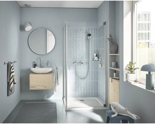 Světlá koupelna se sprchou, umyvadlem, zrcadlem a doplňky pro relaxační atmosféru.