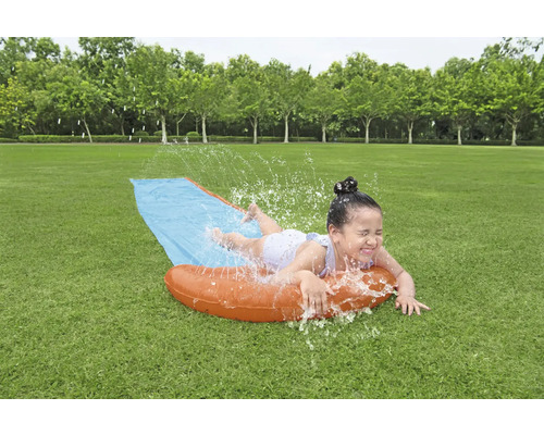 Dívka se baví na vodní skluzavce na zahradě