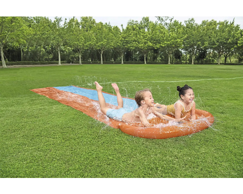 Děti se baví na zahradní vodní skluzavce.