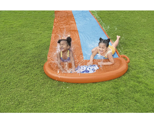 Dvě děti se baví na vodní skluzavce na zahradě.