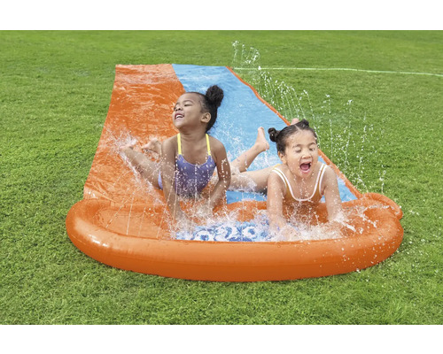 Dvě děti se baví na vodní skluzavce na zahradě.