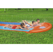 Tři děti kloužou na vodní skluzavce na zahradě.