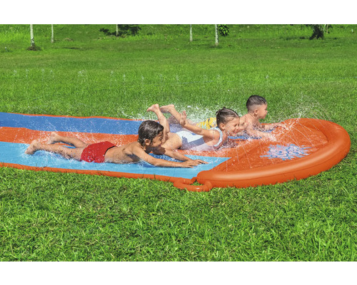 Tři děti kloužou na vodní skluzavce na zahradě.