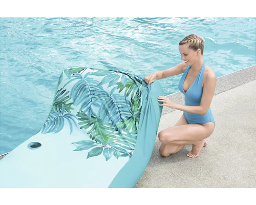 Nafukovací lehátko k bazénu se vzorem listů a ženou u bazénu
