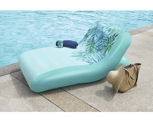 Nafukovací lehátko s tropickým vzorem u bazénu s taškou a kloboukem.